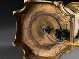a gold clock that has a wire attached to it