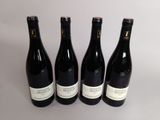 quatre bouteilles de vin sont alignées sur une surface blanche