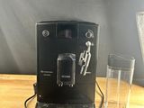 a coffee machine sitting on a wooden table next to a glass of water