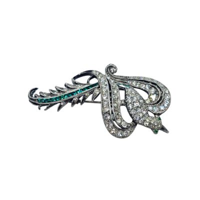 a close up of a brooch with diamonds and emeralds
