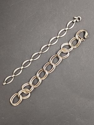 a pair of silver chain bracelets on a black surface