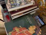 a stack of books sitting on a table next to a chair