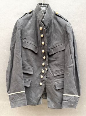 une vieille veste militaire accrochée au mur, à côté d'un mur blanc