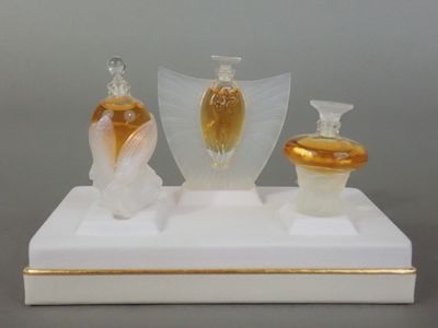 trois vases en verre posés sur un socle blanc orné de dorures