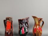 quatre vases de couleurs différentes sont alignés sur une surface grise