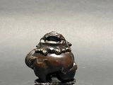 a figurine of a frog sitting on a tree stump