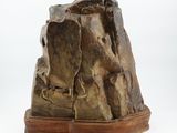 bronze sculpture of a rock on a wooden base on a white background