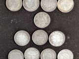 six types différents de pièces d'argent sont disposés sur une surface noire