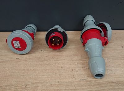 two red and gray electrical plugs sitting on a wooden surface