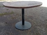 une table ronde avec un piètement en métal au milieu d'une route en gravier