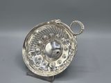 un plat ancien en argent, orné d'un motif circulaire, posé sur un socle