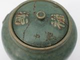 a green pot with writing on it on a white surface