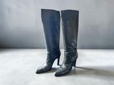 pair of black leather high heeled boots on a concrete floor
