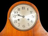 a wooden clock with a silver face on a black background