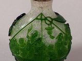 a green and white glass bottle with a red lid