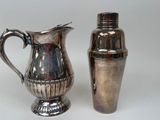 a silver pitcher and a shaker sitting next to each other