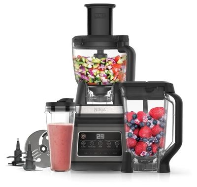 un mixeur contenant des fruits et des légumes, à côté d'un autre mixeur
