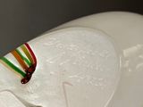 a white ceramic sculpture of a horse with a rainbow ribbon around its neck