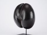 an eggplant sculpture on a black stand against a white background