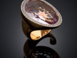a close up of a ring with a purple stone and diamonds