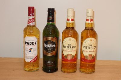 Trois bouteilles d'alcool sont alignées sur une table en bois