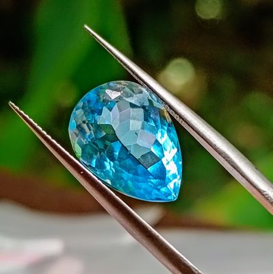 a close up of a blue diamond being held by a pair of tweets