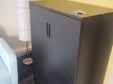 une armoire noire dans une pièce, avec une chaise bleue à côté