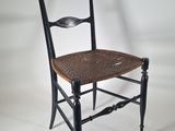 a black chair with a woven seat and a wooden seat
