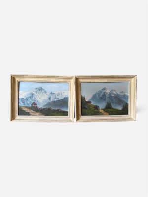 deux tableaux encadrés représentant des montagnes et des maisons accrochés à un mur blanc