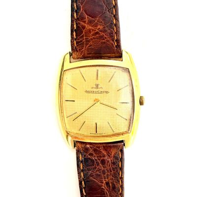 une image représentant une montre en or avec un bracelet en cuir marron sur fond blanc