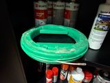 un tuyau vert posé sur une étagère à côté de pots de peinture
