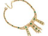 a gold necklace with green stones and fringes on a white background