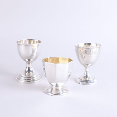 three silver goblets sitting on top of each other on a white surface