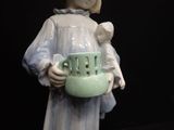 a figurine of a woman holding a green bowl
