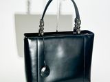 une photo d'un sac à main noir posé sur un présentoir