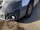 the front end of a white van with a denting front bumper