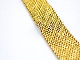 gold colored tie laying on a white surface with a cross in the background