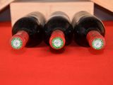 four bottles of wine are lined up in a row on a red table