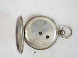 a silver pocket watch on a white surface with a key