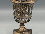 an ornate brass vase with a bird on top of it