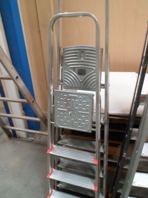 une échelle à côté d'une pile de chaises