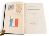 an open book on a white surface with a gold tassel on it