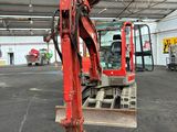 a red excavator that is parked inside of a building