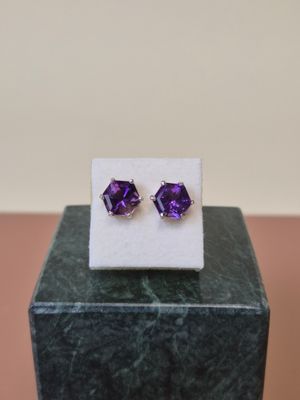 une paire de boucles d'oreilles en améthorate posées sur un bloc de marbre