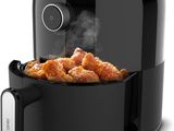 a black air fryer filled with fried chicken sitting on top of a counter