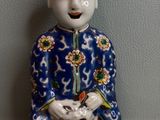 une figurine représentant un homme assis sur un tabouret avec un chat