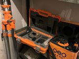 une mallette à outils orange posée sur une étagère, à côté d'un trépied