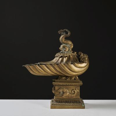 an antique bronze sculpture of a shell with a bird on top