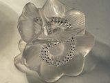 a silver flower shaped object sitting on a white surface