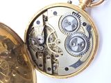 a close up of a pocket watch on a white surface